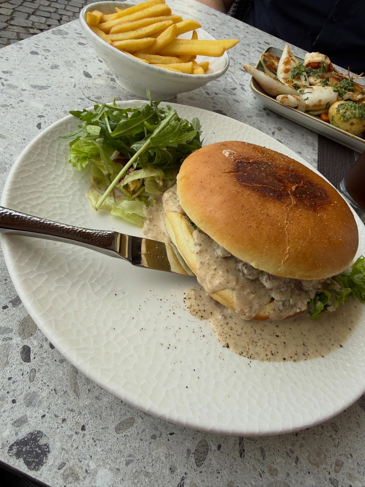 Saftiger Burger mit Champignon-Rahmsauce, dazu Pommes und frischer Rucola